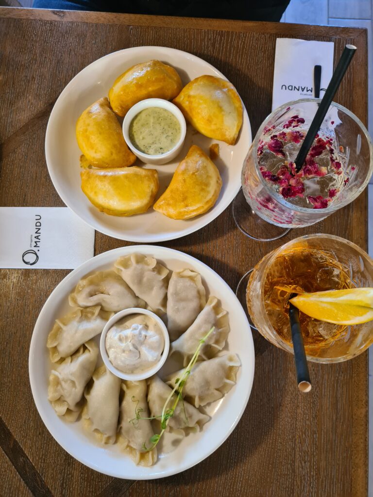 Two plates of pierogies with drinks beside